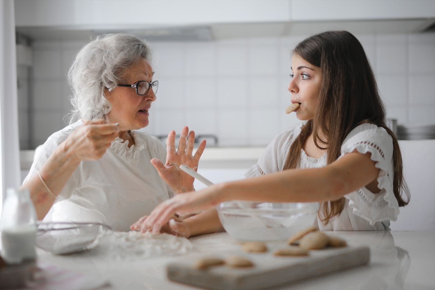 An older woman and a younger woman baking together in a bright home kitchen