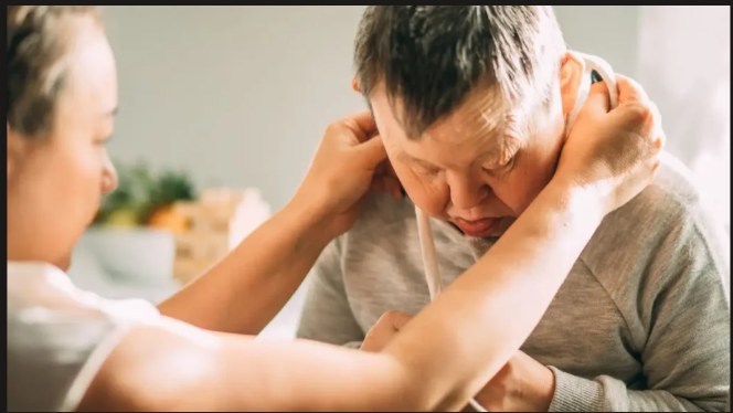 A support worker gently assisting a man with Down syndrome at home